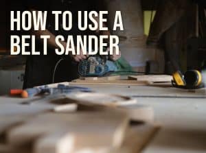 How to use a belt sander: woodworker sanding a board with a handheld belt sander