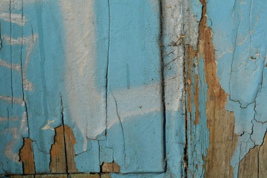 Peeling blue paint on an old wooden door before sanding