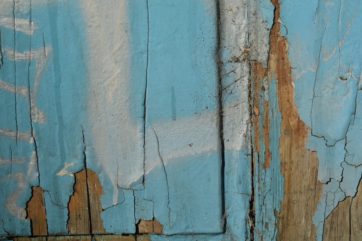 Peeling blue paint on an old wooden door before sanding