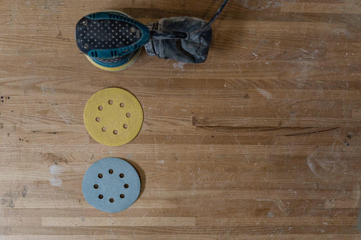 Random orbital sander and two 8-hole sanding discs on a workbench