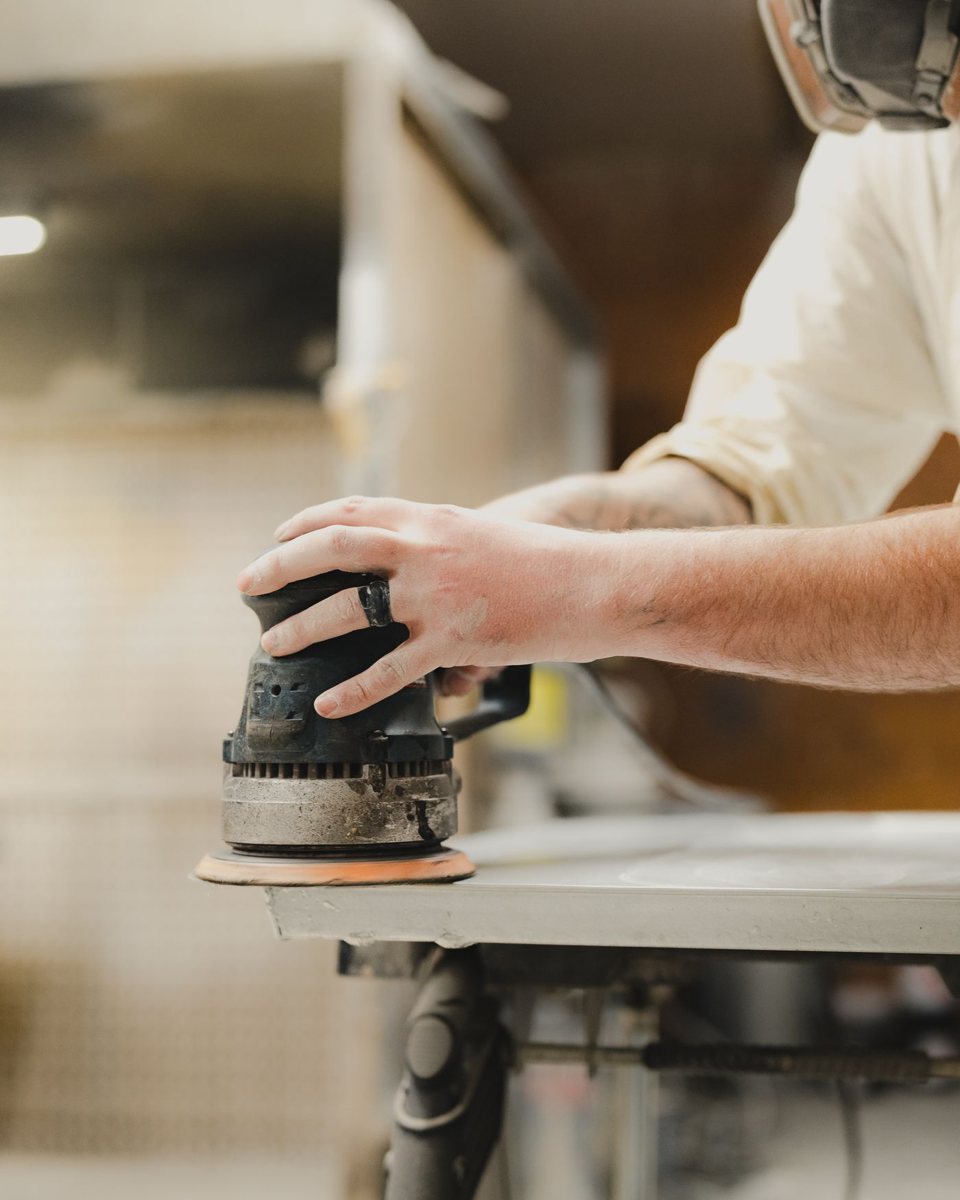 Hand guiding a random orbital sander along the edge of a panel