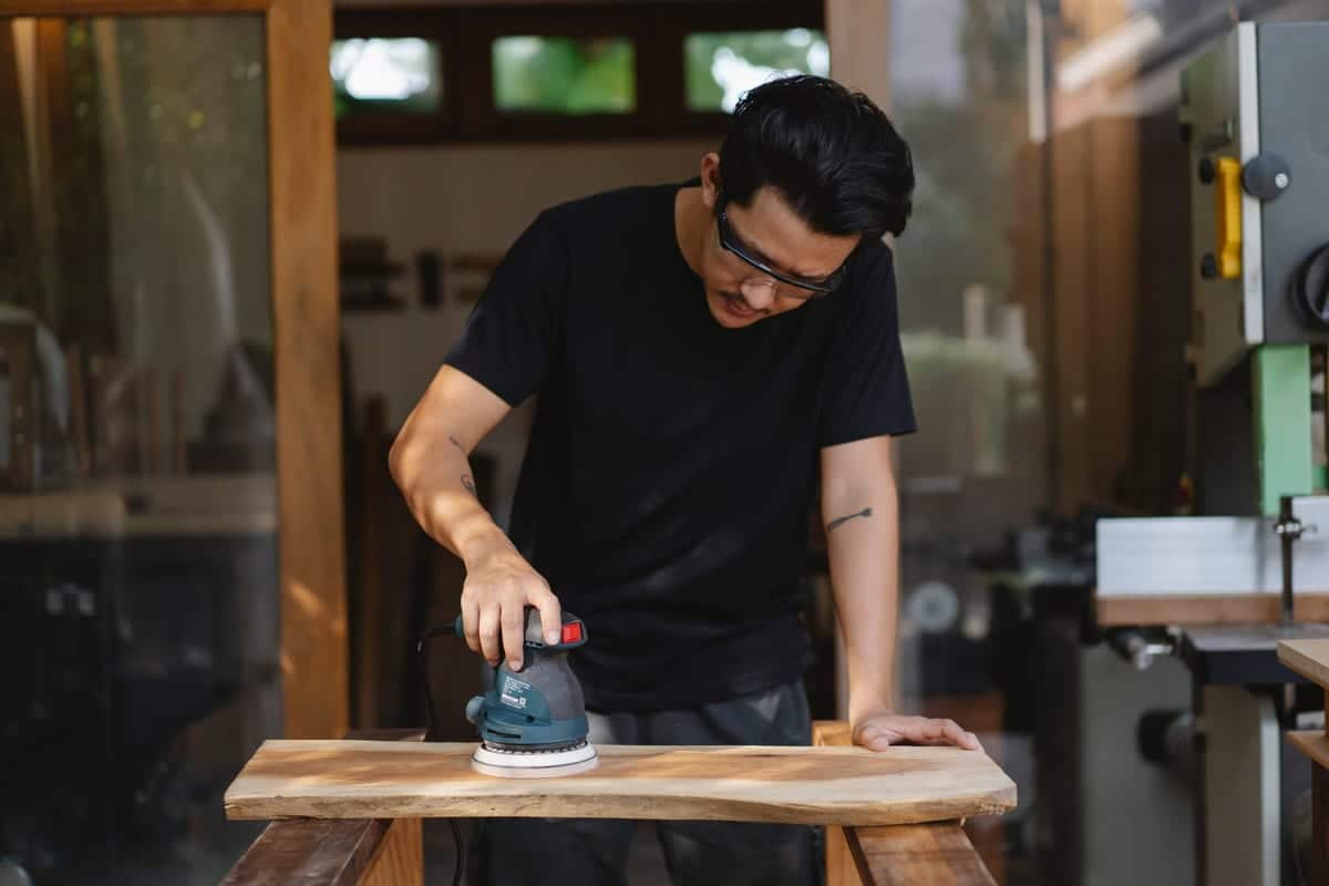 Random orbital sander on a wooden tabletop during furniture refinishing
