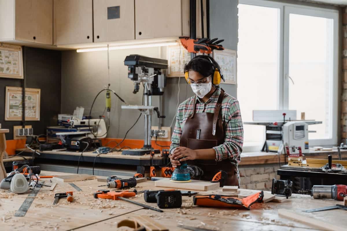 Woodworker sanding with a dust mask, safety glasses and hearing protection