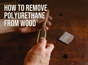 How to remove polyurethane from wood: a woodworker holding a scraper over an old finished workbench