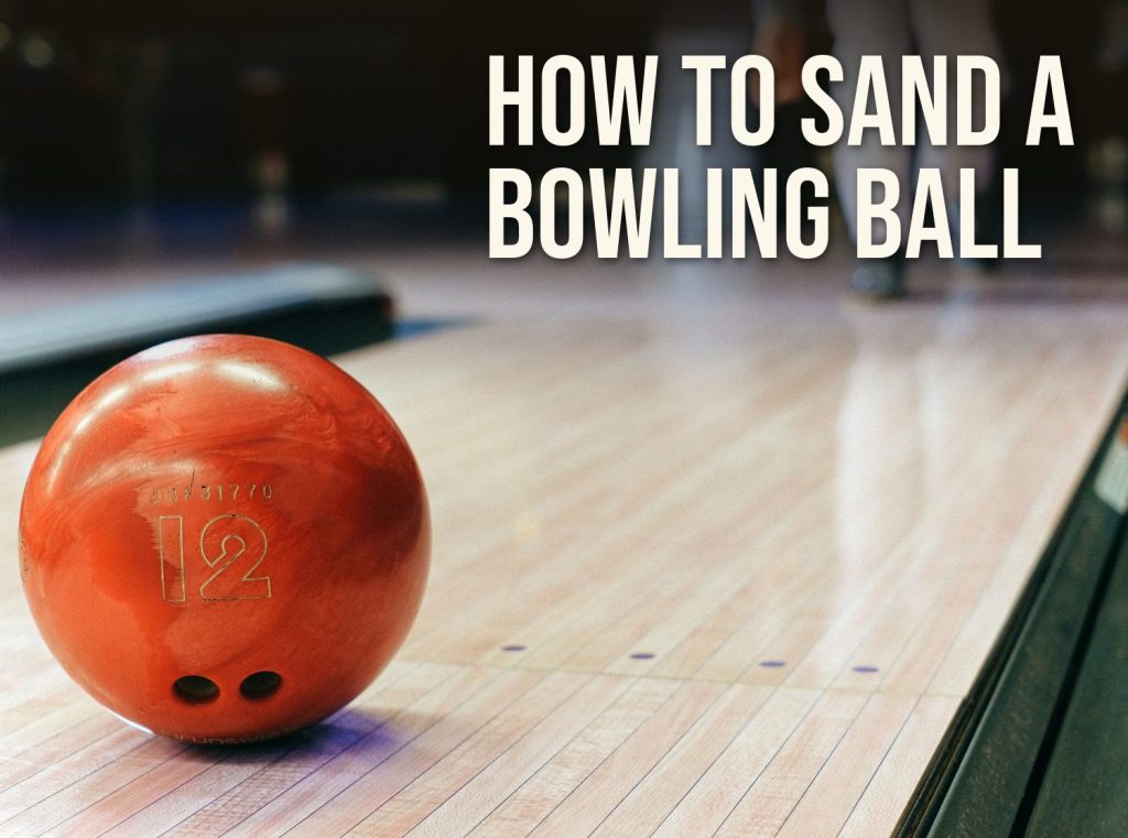 How to sand a bowling ball: a red bowling ball resting on a wooden bowling lane