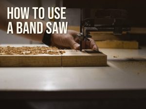 How to use a band saw: a woodworker feeding a board into a band saw blade with the upper guide set close to the wood