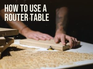 How to use a router table: a woodworker feeding a board past a bearing-guided bit on a router table