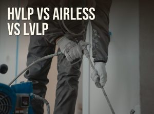 HVLP vs airless vs LVLP: a painter holding an airless spray gun on its hose next to the pump