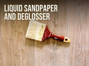 Liquid sandpaper and deglosser: a used paintbrush lying on a wood floor ready for repainting