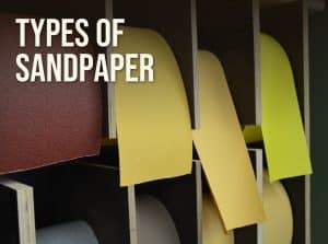 Types of sandpaper: rolls of red, yellow and green abrasive paper in a workshop rack